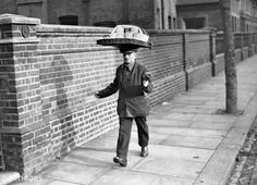 an old man with a bag on his head walking down the street in front of a brick wall