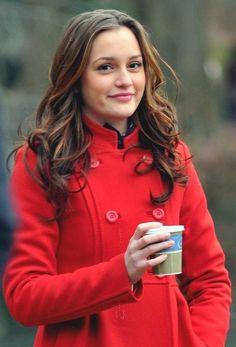 a woman in a red coat holding a coffee cup