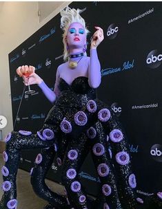 a woman dressed in black and purple is posing for the camera with an octopus like costume on