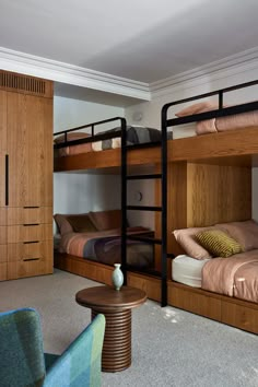 a bedroom with bunk beds and two chairs in front of the bed is made of wood