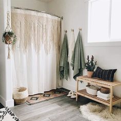 a bathroom with white walls and wooden floors, rugs on the floor, shower curtain