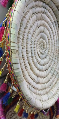 a woven basket with tassels and beads hanging from it's sides on display