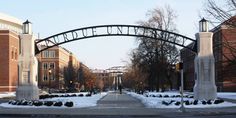 an arch in the middle of a street with snow on the ground and buildings behind it