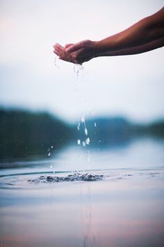 someone is holding their hand out to the water