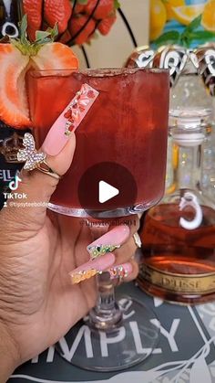 a person holding up a drink in front of a table with strawberries on it