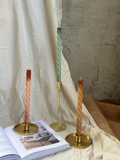 two candles sitting on top of a table next to an open book