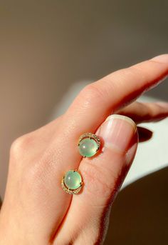 This pair of top quality Burmese jade stud earrings is just stunning. The unique moonlight light green color is extremely translucent and delicate looking. The jade is surrounded by dainty diamonds to illustrate the illumination of the amazing gemstones. A special pop of elegant color on your ear will receive so much compliments. Jade Stud Earrings, Luxury Green Jade Earrings, Fine Jewelry In Yellow Gold With Chalcedony, Elegant Oval Jade Jewelry, Yellow Gold Jade Jewelry With Cabochon, Yellow Gold Pierced Jade Jewelry, Green Diamond Accented Round Earrings, Green Round Earrings With Diamond Accents, Green Diamond Pierced Earrings