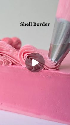 a pink cake with icing being applied to it