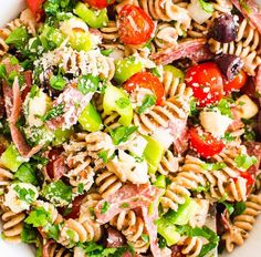 a bowl filled with pasta salad and lots of toppings on top of the salad