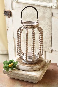 an old lantern with beads on it sitting on a table next to a flower pot