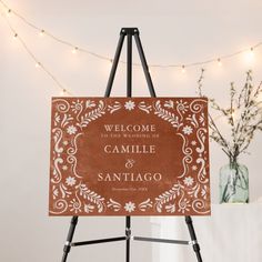 a welcome sign is displayed on an easel in front of a string of lights