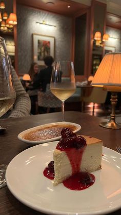 a piece of cheesecake on a plate next to a glass of wine