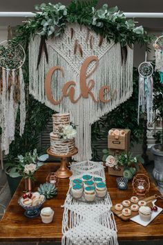 a table with cakes and cupcakes on it in front of a cake sign