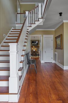 a chair sitting in the middle of a room next to a stair case and wooden floors