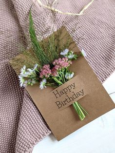 a birthday card with flowers on it sitting on top of a table next to a blanket