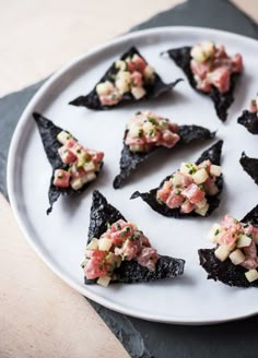 a white plate topped with black food on top of a wooden table