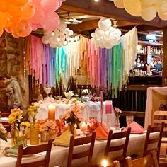 a dining room filled with lots of tables covered in white tablecloths and balloons