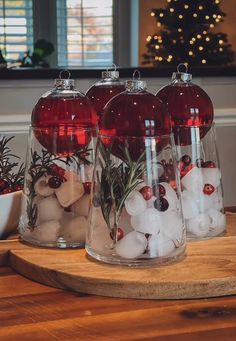 three clear glass vases filled with red and white ornaments on top of a wooden table