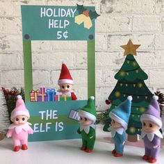 three elf figurines are standing in front of a sign that says holiday help $ 5 the elf is