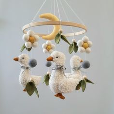 three stuffed animals hanging from a mobile with leaves on it's sides and a moon in the background