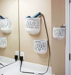 the bathroom is decorated in white and has three soap dispensers hanging on the wall