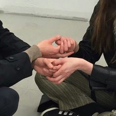 three people sitting on the floor holding hands together