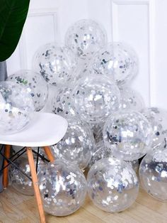 a pile of shiny balls sitting on top of a wooden floor next to a plant