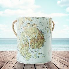 a map bucket sitting on top of a wooden table next to the ocean and sky