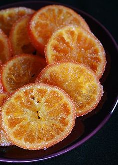 sliced oranges on a purple plate with black background