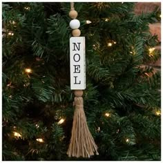 a christmas ornament hanging from a tree with the word noel written on it