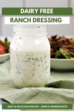 a mason jar filled with ranch dressing on top of a green table cloth next to a bowl of salad