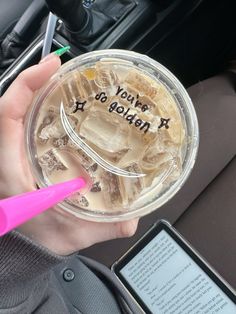 a person holding up a plastic cup with ice and water in it that says you're golden