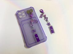 a purple phone case sitting on top of a table next to a pair of earrings