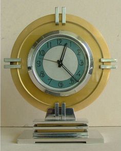 a clock that is sitting on top of a stand in front of a white wall