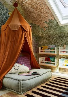 an orange canopy bed in a child's room with bookshelves on the wall