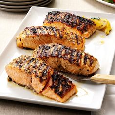 three grilled salmon fillets on a white plate