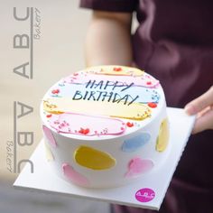 a woman holding a birthday cake with the words happy birthday written on it