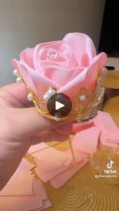 a hand holding a pink rose with pearls on it