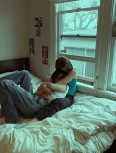 a man and woman laying in bed with their arms around each other's shoulders