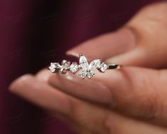 a woman's hand holding an engagement ring with three small diamonds on the side