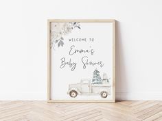 a baby shower sign on the floor in front of a white wall with a wooden frame