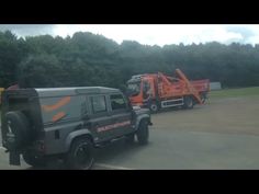 two tow trucks parked next to each other on a parking lot with trees in the background