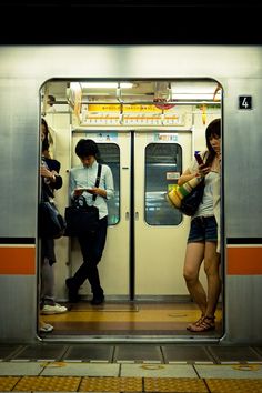 two people standing on a subway platform looking at their phones