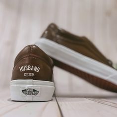 two brown and white shoes sitting on top of a wooden floor next to each other