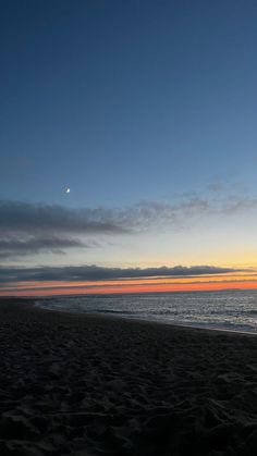 the sun is setting at the beach with no one on it