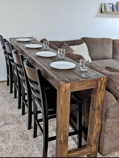 a long table with plates and glasses on it in the middle of a living room