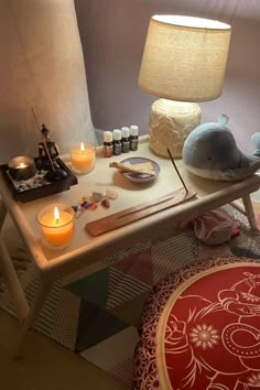 a wooden table topped with candles next to a lamp and a stuffed animal on top of it