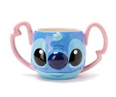 a blue and pink coffee cup with an adorable face on the side, sitting in front of a white background