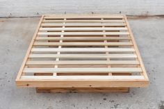 a wooden bed frame sitting on top of cement