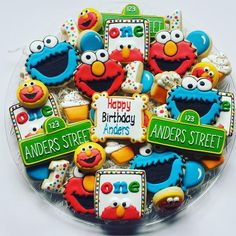 decorated cookies in the shape of sesame street characters on a clear plate with happy birthday sign